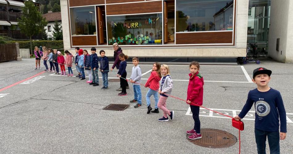 Kinder stehen in einer Schlange und halten sich an einer Schnur