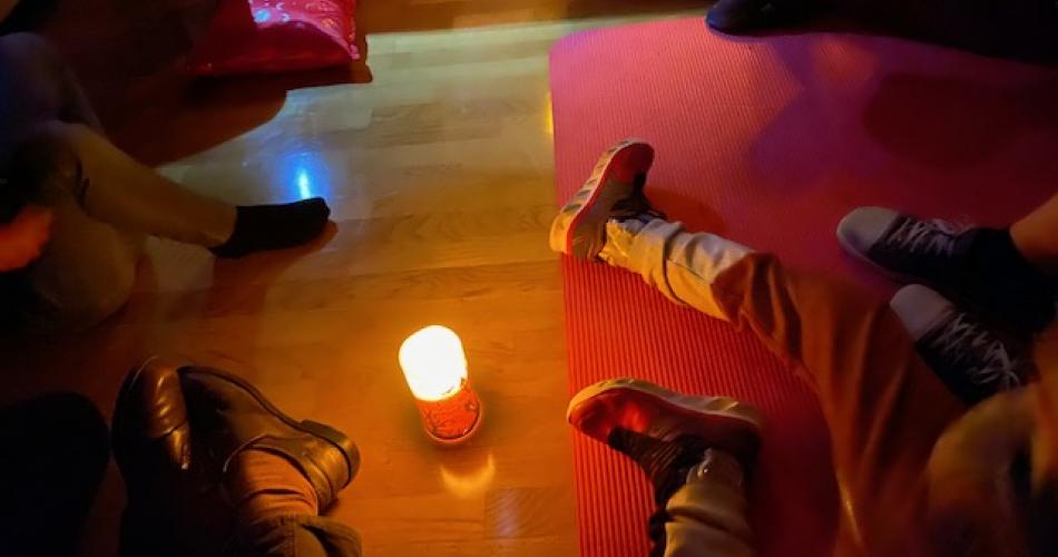 Kerze am Boden, die Füße der Kinder ringsherum