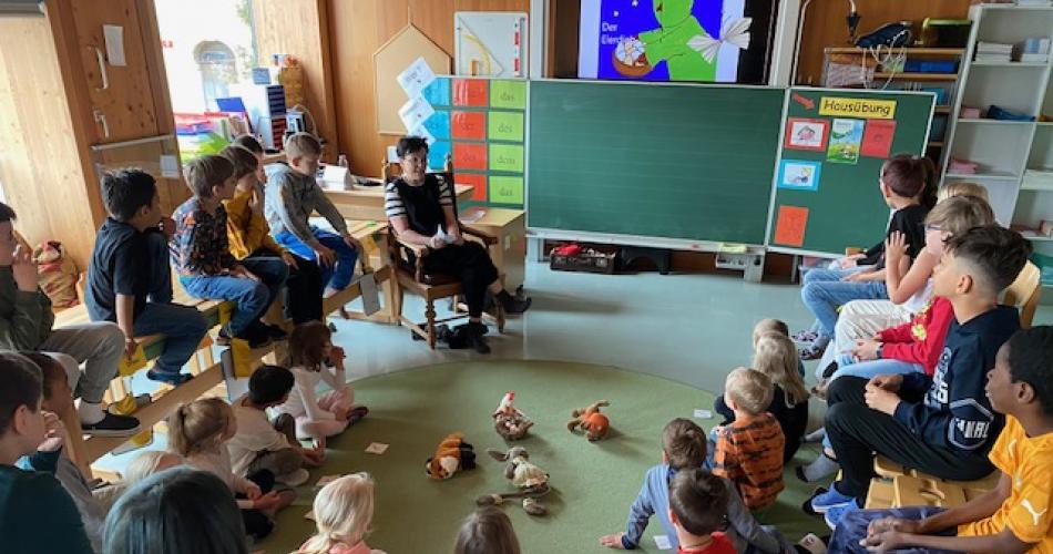 3.Klass-Kinder und KIGA-Kinder sitzen im Halbkreis in der Klasse