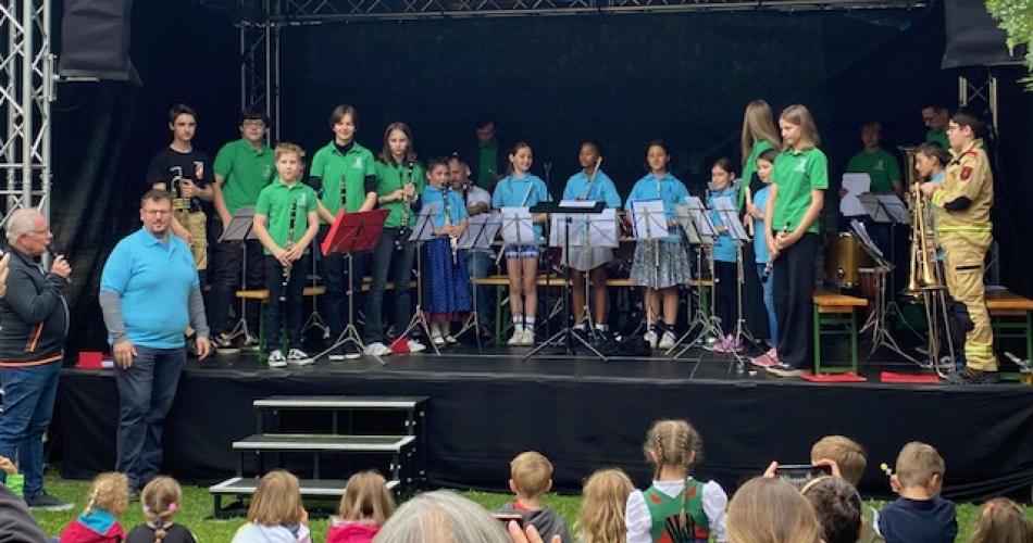 Kinder der Bläserklasse stehen auf einer Bühne im Freien