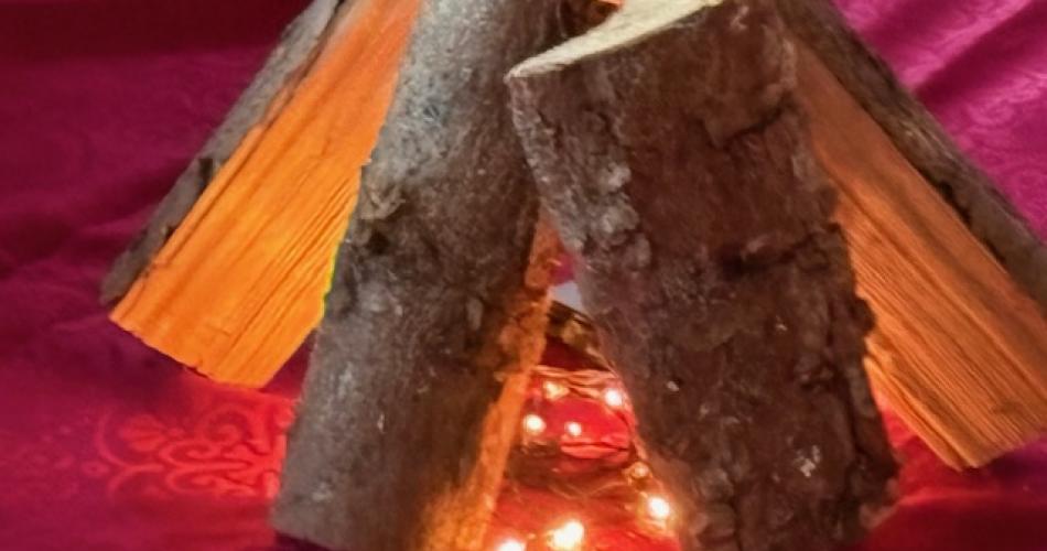 Holzscheite und eine Lichterkette symbolisieren ein Feuer