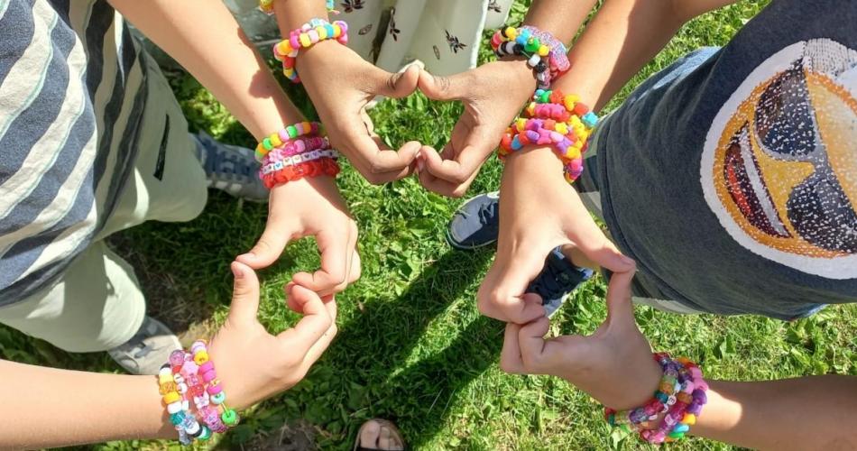 Kinder mit bunten Armbändern zeigen mit den Fingern Herzen