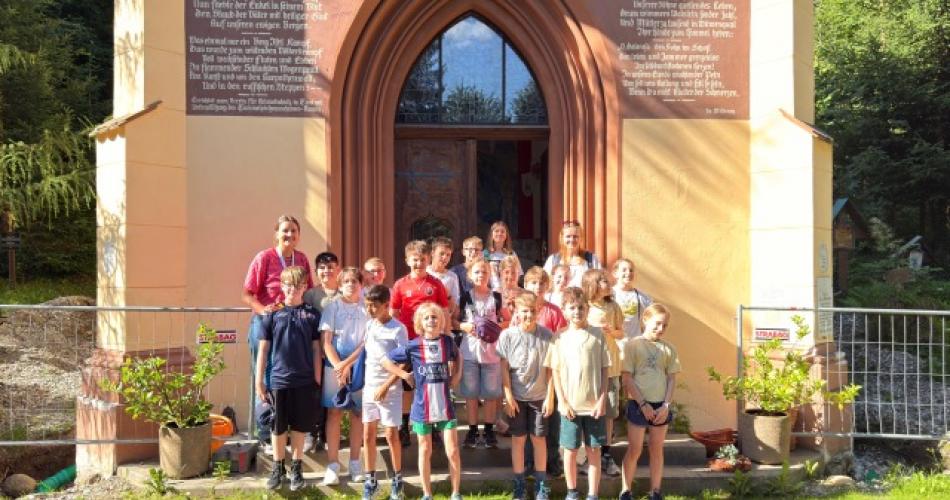Gruppe Kinder steht mit Pfarrer und Religionslehrerin vor der Kapelle
