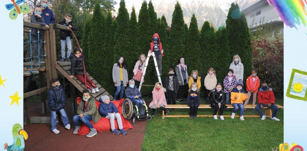 Klasse 1a sitzt im Garten und am Klettergerüst mit Masken