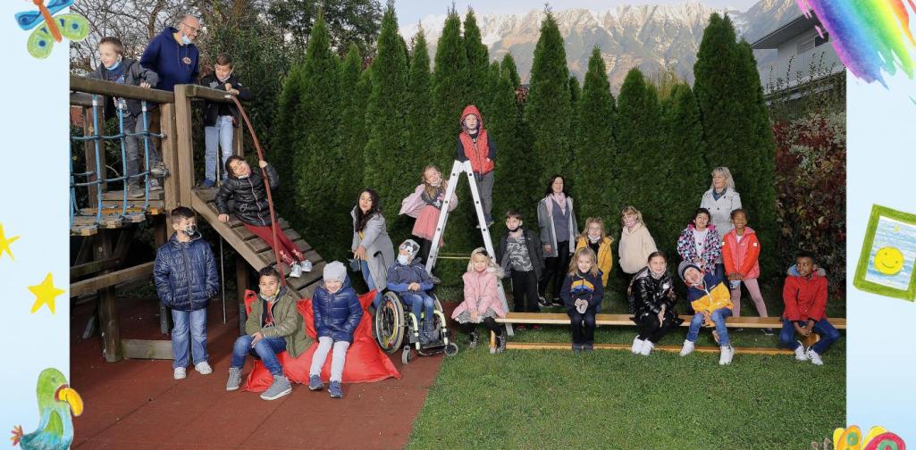 Klasse 1a sitzt im Garten und am Klettergerüst