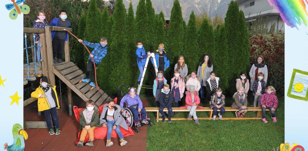 Klasse 1b sitzt im Garten und am Klettergerüst mit Maske