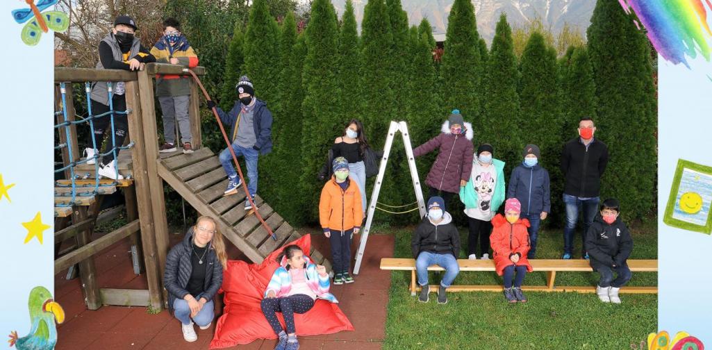 3a-Kinder sitzen im Garten und am Klettergerüst - mit Maske