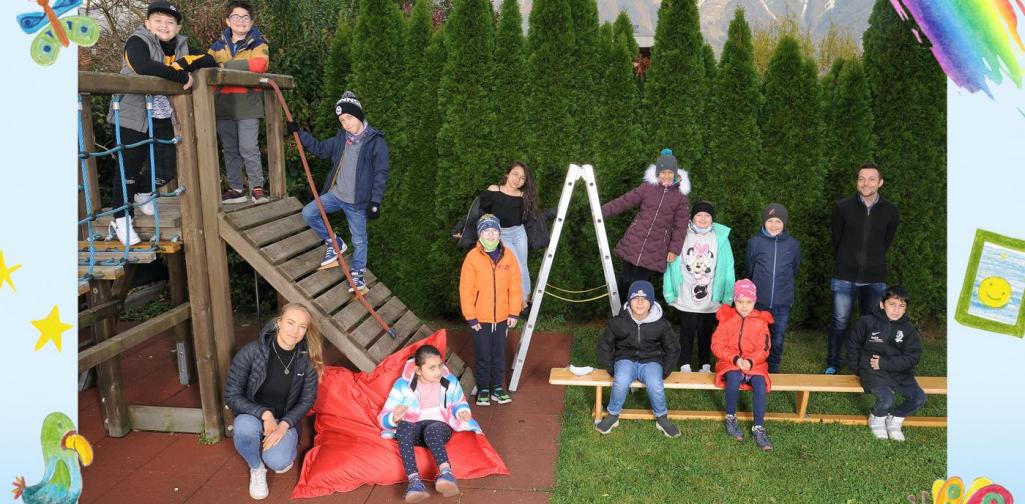 3a-Kinder sitzen im Garten und am Klettergerüst