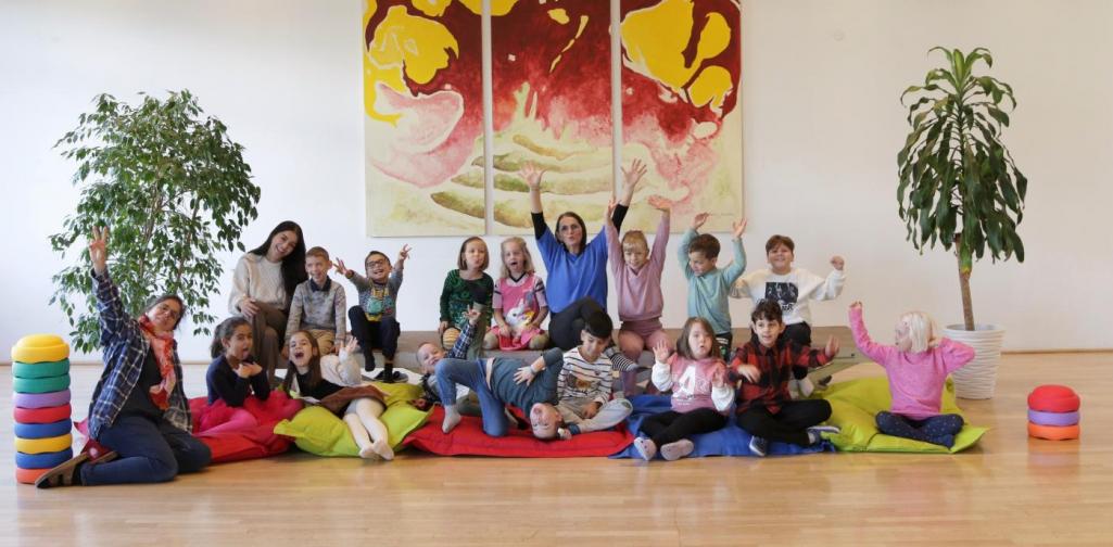 Kinder und Lehrpersonen lachen in die Kamera