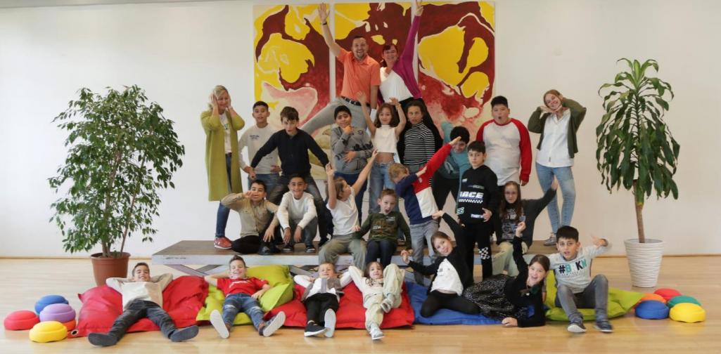 Kinder und Lehrpersonen lachen in die Kamera