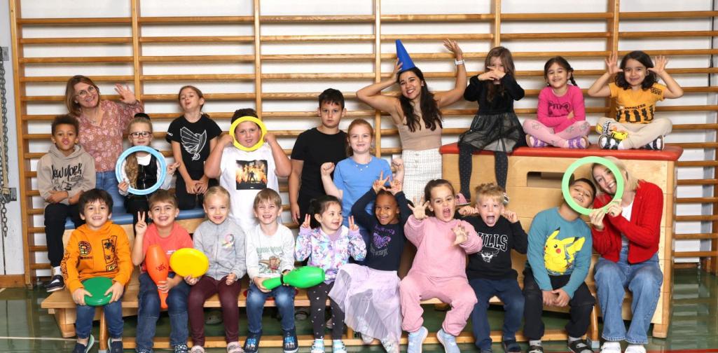 1b macht Unsinn auf Langbänken und Kästen mit buntem Spielmaterial im Turnsaal.