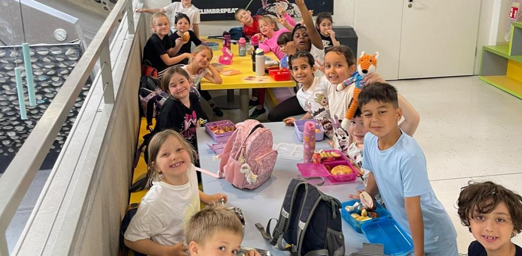 Schülerinnen und Schüler machen während ihres Besuchs in der Kletterhalle gemeinsam eine Jausenpause.