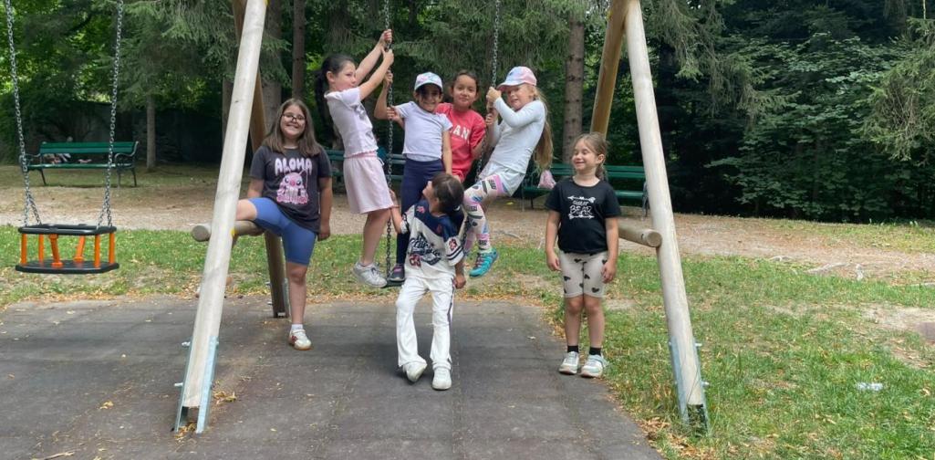 Kinder klettern, schaukeln und spielen gemeinsam auf dem Spielplatz im Schlosspark