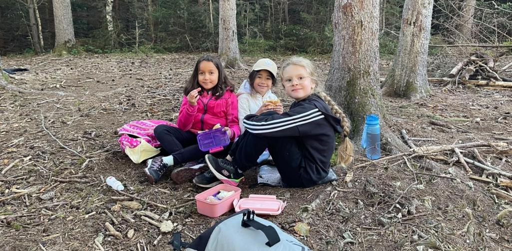 VS Amras Drei Kinder sitzen während der Jausenpause gemeinsam im Wald.