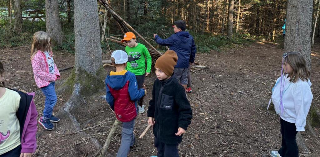 VS Amras Kinder sammeln Äste und bauen gemeinsam einen Unterschlupf im Wald.